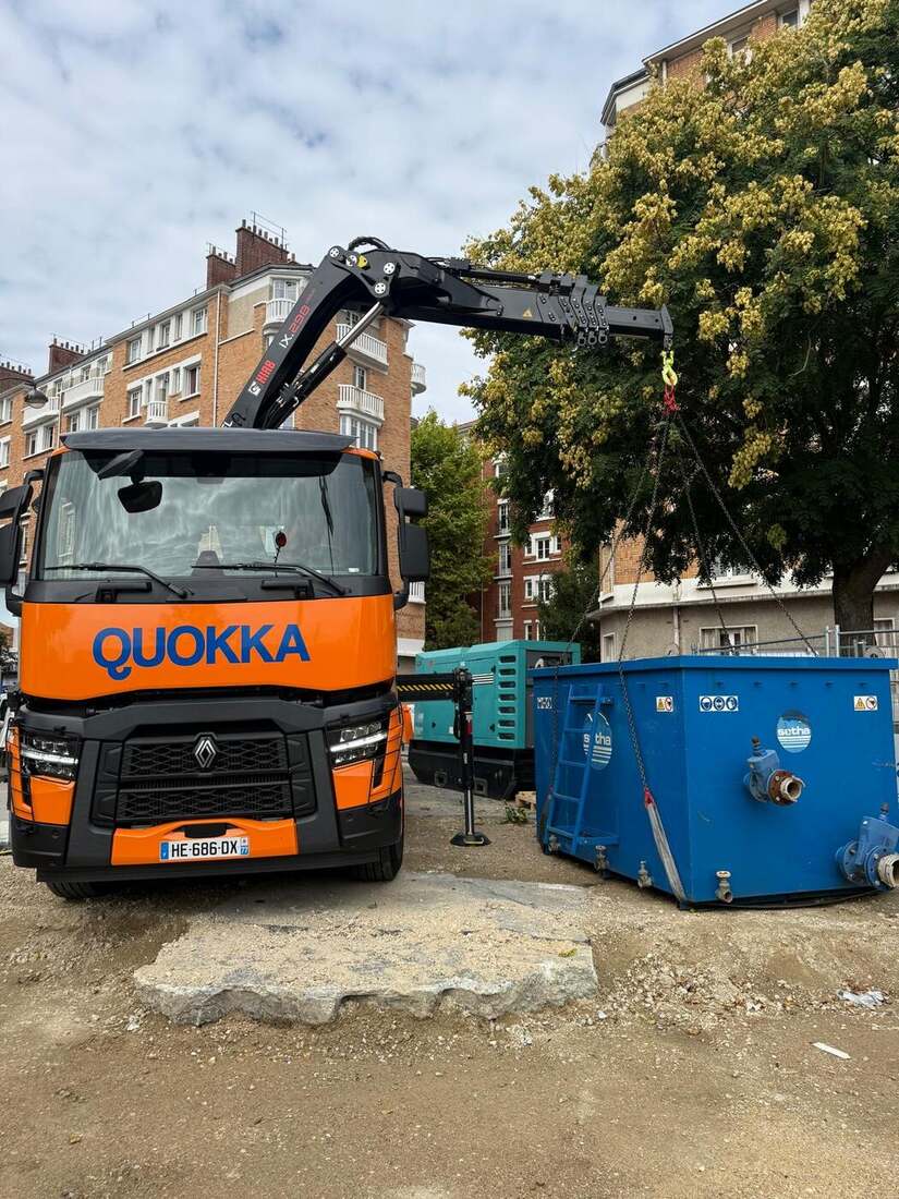 Camion-grue Quokka soulevant une benne près d'un arbre